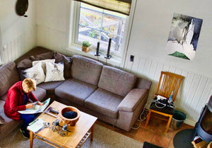 Fine-Art Poster „Blatt 17.6“ aus dem „Blauen Skizzenbuch“ von johann franki in einem gemütlichen Appartement mit weißer Rauhfaserwand, Sitzecke und Ofen – das abstrakt-landschaftliche Motiv im Hochformat DIN A2 zeigt turmähnliche Strukturen.