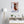 Fine-Art Poster „Blatt 6.2 aus dem „Blauen Skizzenbuch“ von johann franki in einem Arbeitszimmer mit weißgekalkter Wand, Stehlampe und Sideboard – das  Motiv im Hochformat zeigt eine Figur auf einem schwebendem Board.
