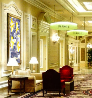 Fine-Art Poster „Blatt 35“ aus dem „Blauen Skizzenbuch“ von johann franki in einem ehrwürdigen Hotelfoyer als Hintergrund einer Sitzgruppen – das abstrakt-musterhafte Motiv im Hochformat zeigt gelbe Strukturen auf payne-blaue Hintergrund.
