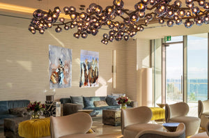 Fine-Art Poster „Blatt 5 und Blatt 6“ aus dem „Blauen Skizzenbuch“ von johann franki im Lobbybereich eines Hotels, – die  Motive im Hochformat zeigen abstrakte Figuren in einer angedeuteten Szenerie mit dezenten, zum Teil kräftigen Farben.
