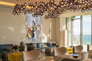 Fine-Art Poster „Blatt 6“ aus dem „Blauen Skizzenbuch“ von johann franki als Sondergröße im Lobbybereich eines Hotels, – das  Motiv im Hochformat zeigt abstrakte Figuren in dezenten zum Teil kräftigen Farben.