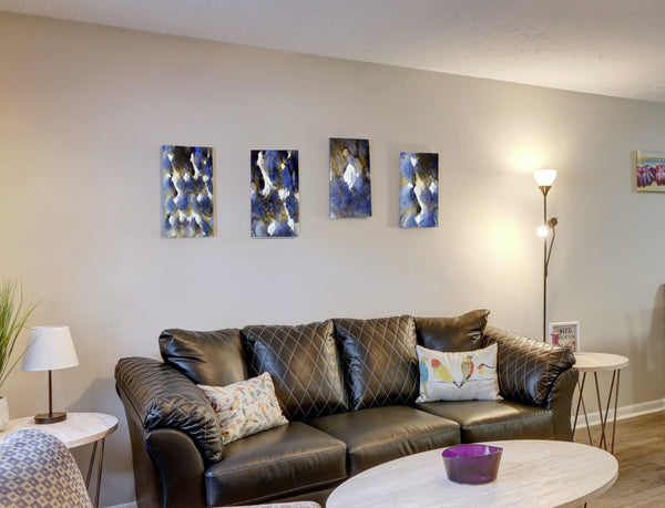 Fine-Art Poster „Blatt 11.1-.2-.3-.4“ aus dem „Blauen Skizzenbuch“ von johann franki in einem hellen Wohnzimmer über einer hellen Couch, – die  Motive in Hochformaten zeigen in größe DIN A4 die blaue Serie von 4 musterhaften Abstraktionen.
