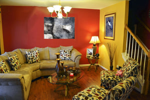 Fine-Art Poster „Blatt 42.1“ aus dem „Blauen Skizzenbuch“ von johann franki über einer hellen Couch an knallroter Tapete, – das  Motiv im Querformat zeigt eine abstrakte Komposition payneblauen Tönen. 