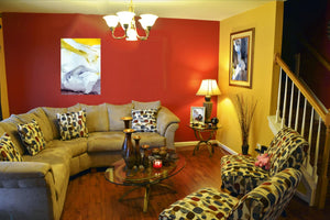 Fine-Art Poster „Blatt 43.3“ aus dem „Blauen Skizzenbuch“ von johann franki über einer hellen Couch an knallroter Tapete, – das  Motiv im Hochformat zeigt eine abstrakte Komposition in hellen Tönen mit Gelb. 
