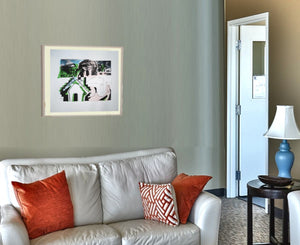 Mockup Wartebereich mit 2-Sitzcouch, darüber im Rahmen und Pssepartout das Webslammotiv Haus von 2011.